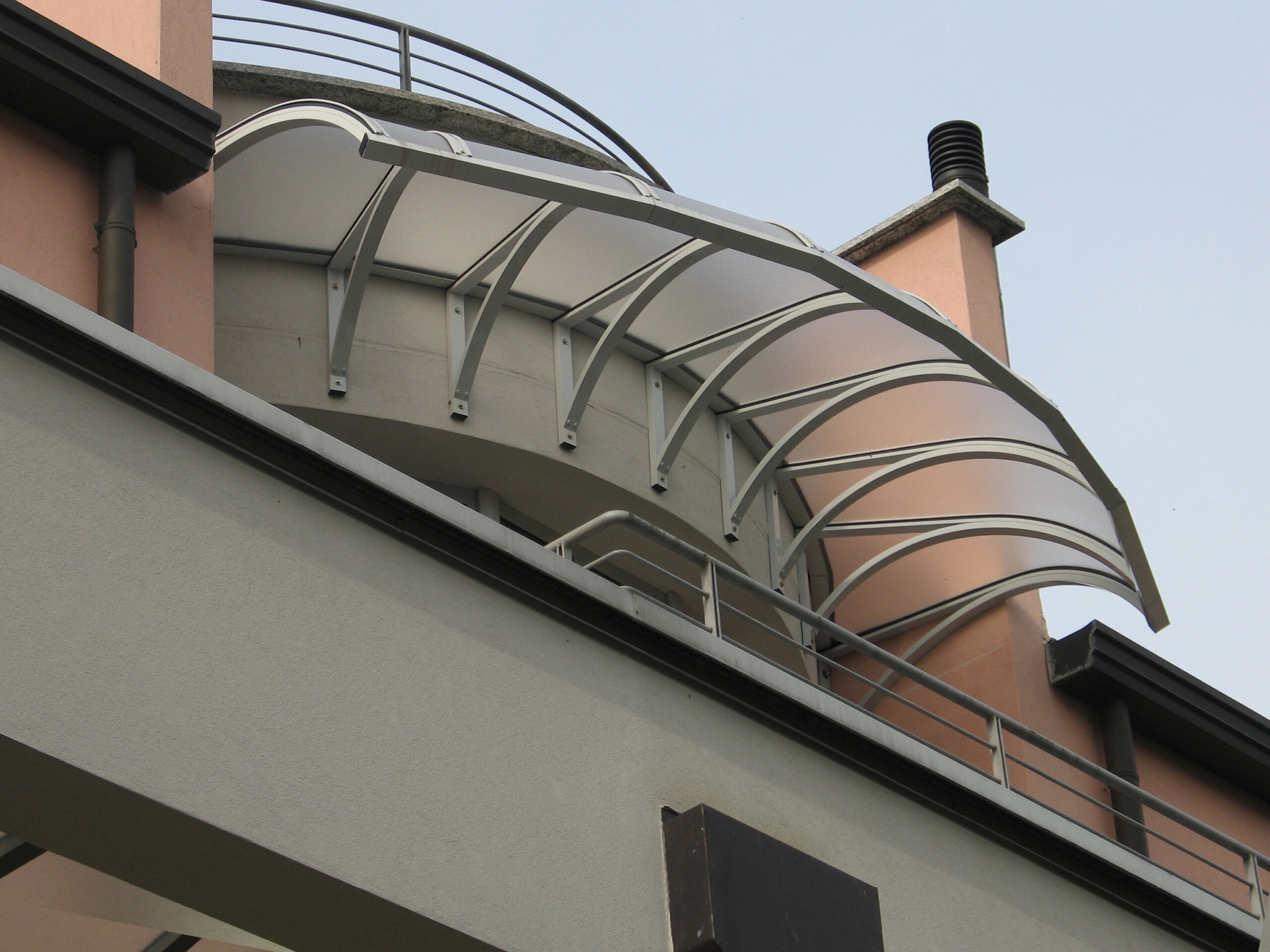Pensilina curva P3 sotto terrazza panoramica arrotondata Pensilina curva P3 in alluminio bianco installata sotto una terrazza panoramica arrotondata di un edificio residenziale