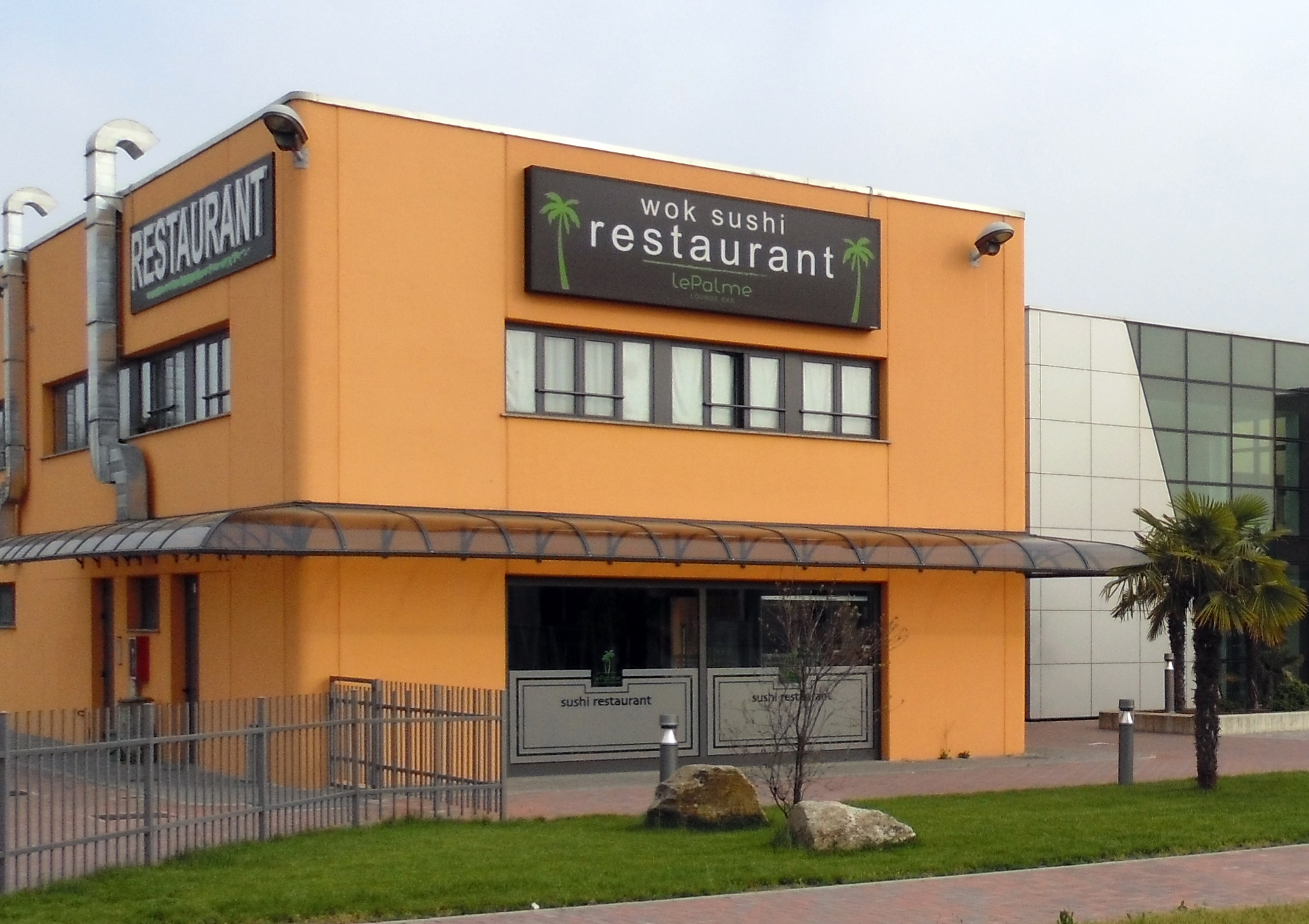 Pensilina curva P3 su facciata di un ristorante Pensilina curva P3 antracite con lastra trasparente installata sulla facciata di un edificio commerciale con ristorante