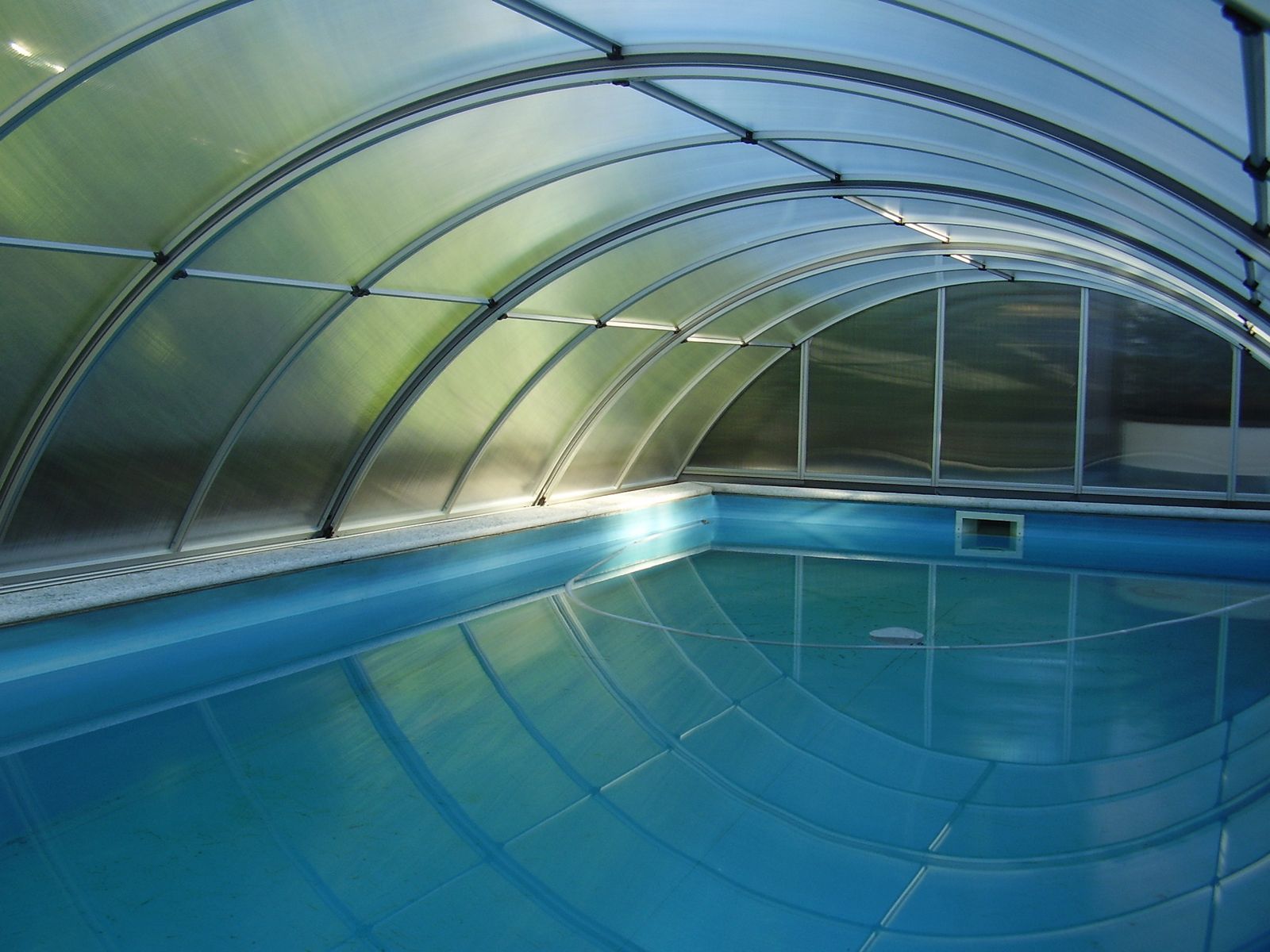 Copertura per piscine - interno con vasca piena Vista interna di una copertura per piscine con vasca colma d'acqua e struttura ad arco in policarbonato