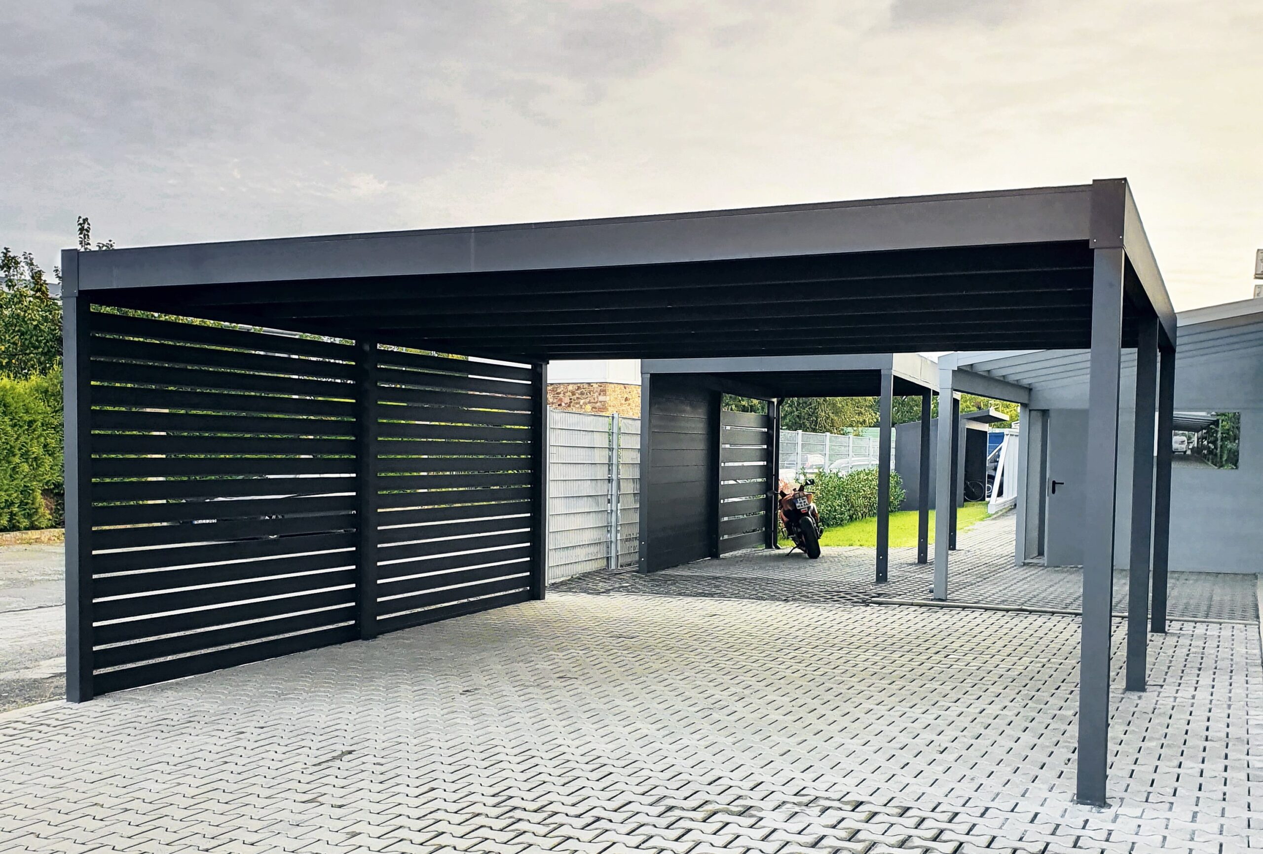 Pensilina per auto piano con parete laterale in legno Carport a tetto piano con struttura antracite e parete laterale effetto legno, addossato alla casa