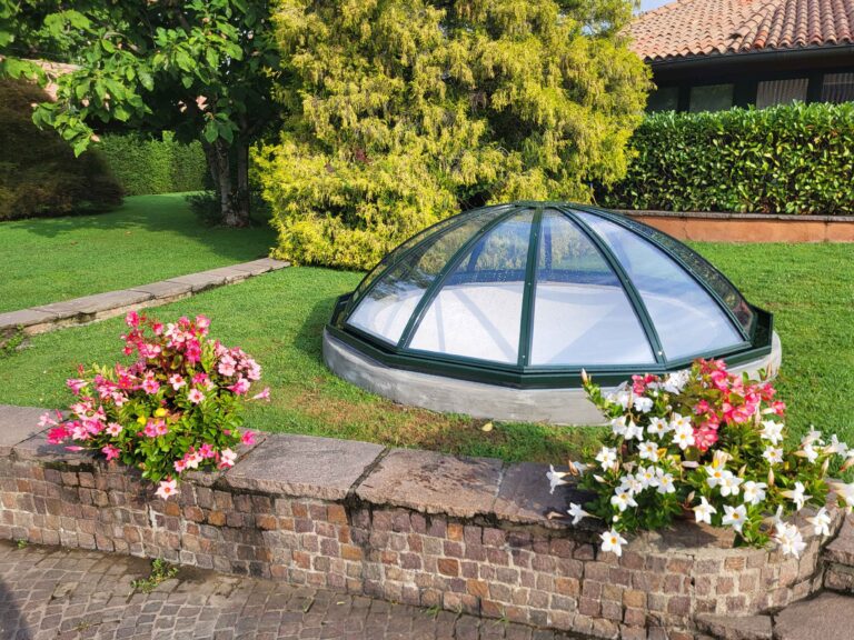 Piccola cupola a base poligonale Jolly installata come lucernario da giardino, circondata da fiori