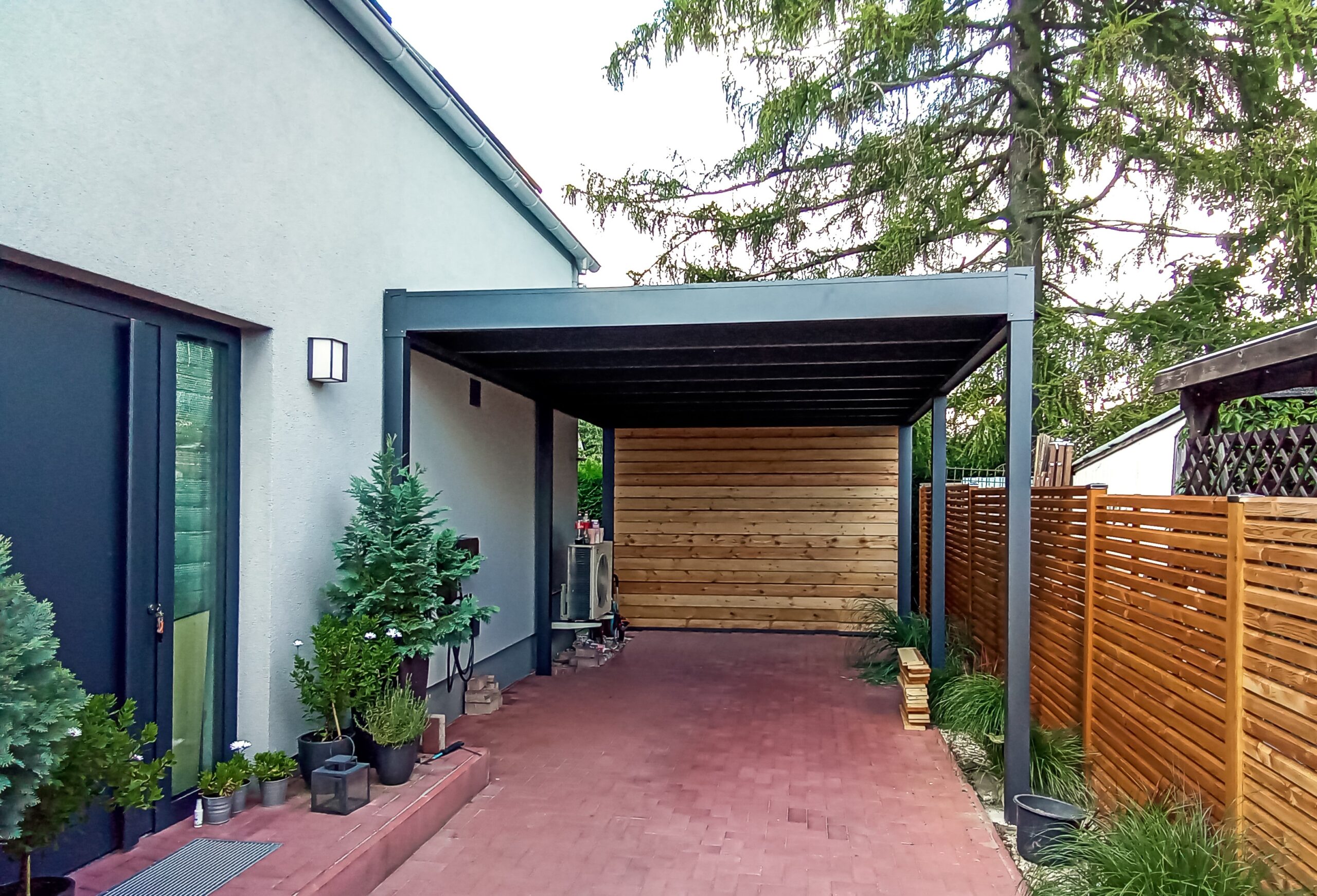 Pensilina per auto piano doppia con parete in legno Carport doppio a tetto piano in alluminio antracite con parete laterale in doghe di legno e pavimentazione in autobloccanti