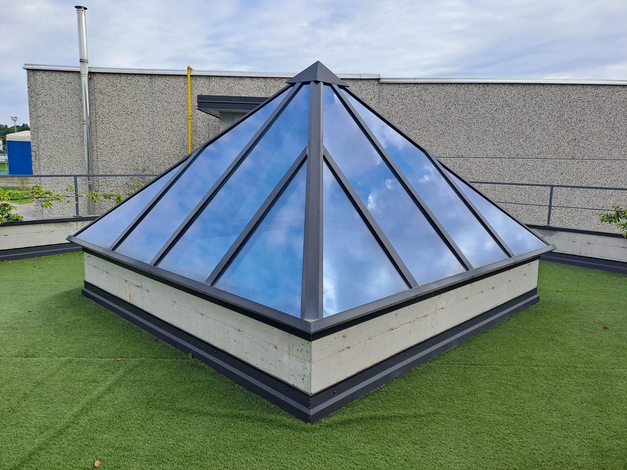 Lucernario a piramide a base quadrata su terrazza Lucernario a piramide a base quadrata installato su una terrazza con pavimentazione in erba sintetica